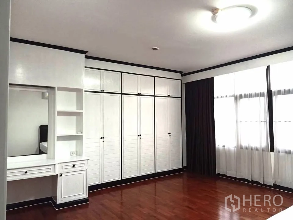 Condominium for rent in Watthana, Bangkok - Bedroom corner featuring a wall of built-in wardrobes, dressing table, and large windows.