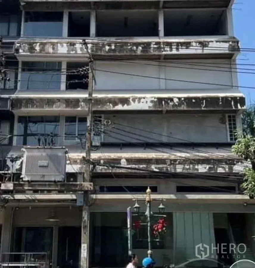 Shophouse for rent in Watthana, Bangkok - Multi-storey shophouse facade with weathered concrete and street cables in Bangkok.