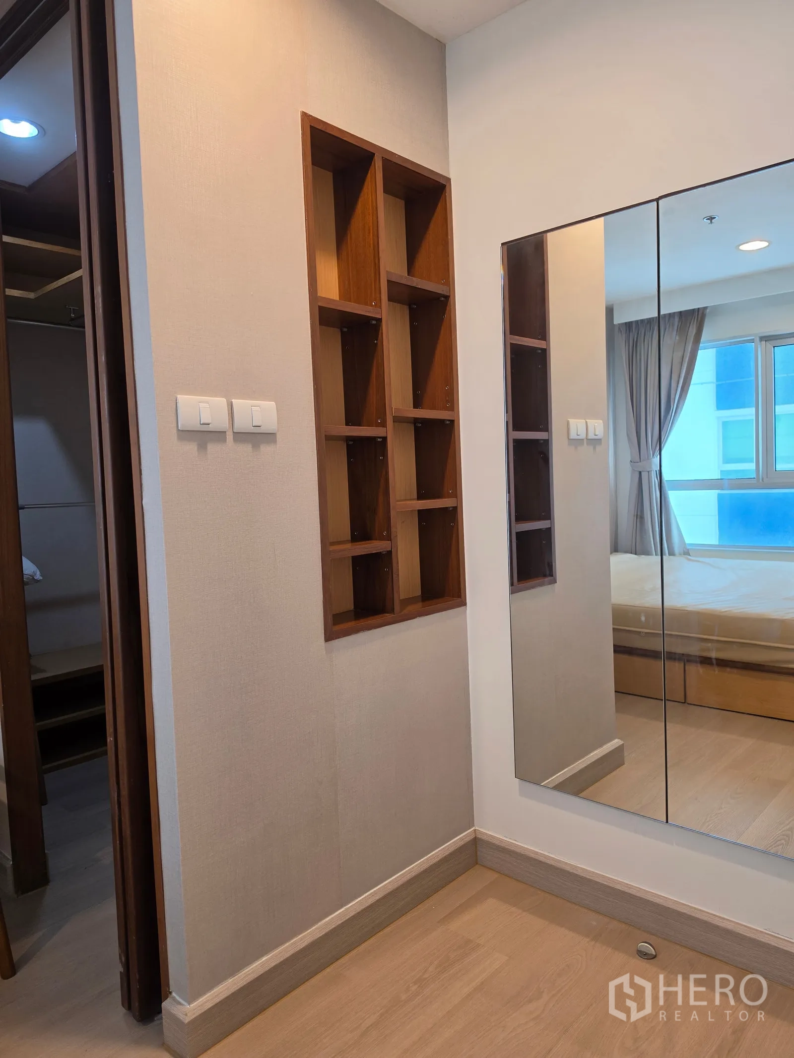 Condominium for rent in Huai Khwang, Bangkok - Hallway corner with wall mirror and recessed wooden display shelves.