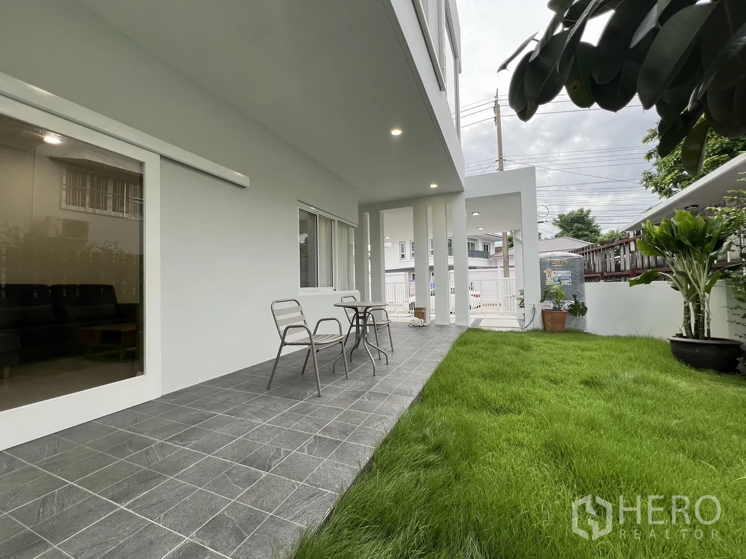 Detached House for rent in Saphan Sung, Bangkok - Covered terrace with two chairs beside large sliding doors.
