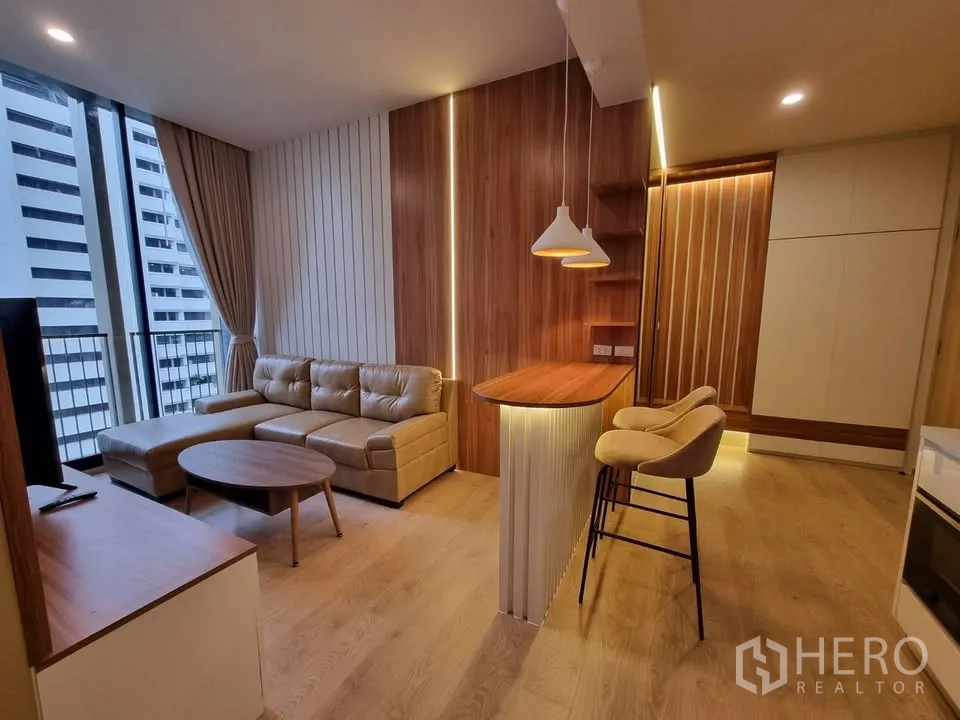คอนโด for rent in Watthana, Bangkok - ห้องนั่งเล่นโทนไม้พร้อมโซฟาเข้ามุม เคาน์เตอร์บาร์ เก้าอี้สูง โคมไฟแขวน และหน้าต่างเต็มบานพร้อมม่านกันแสงและวิวเมือง