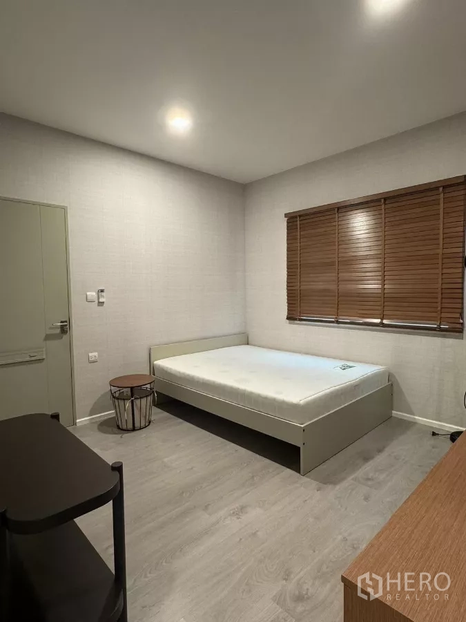 Detached House for rent in Prawet, Bangkok - Guest bedroom with wood blinds, bed and laminate flooring.