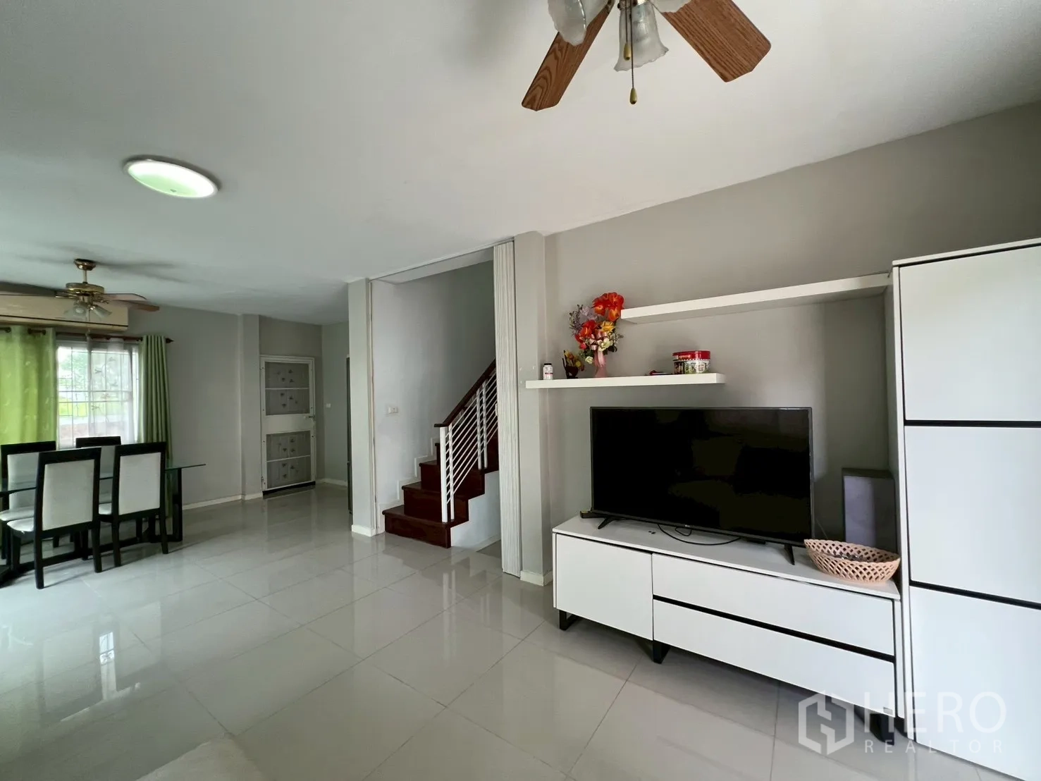 บ้าน ขายในMin Buri, Bangkok - ผนังทีวี ชั้นวางของ และบันไดในห้องนั่งเล่นกว้าง