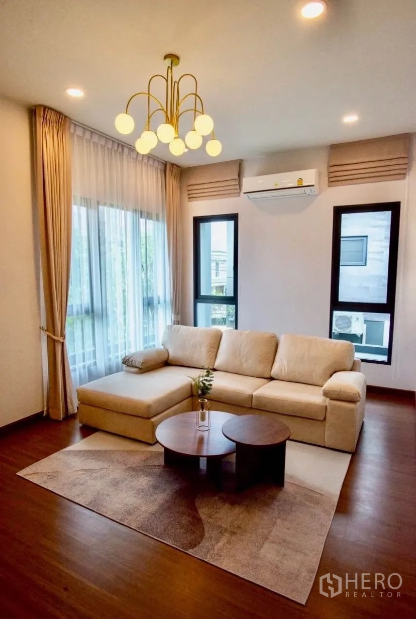 独立式住宅 出租在Bang Phli, Samut Prakan - 二层家庭区，米色沙发、现代吊灯与木地板。