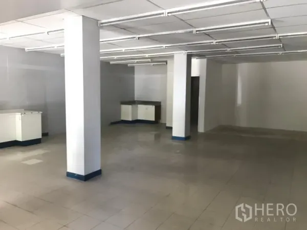 零售空间 出租在Watthana, Bangkok - 店内开放式空间，瓷砖地面、白色立柱与满铺日光灯。