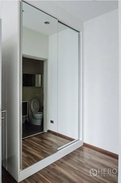 Condominium for rent in Khlong Toei, Bangkok - Hallway featuring a full-height mirrored wardrobe reflecting wood flooring.