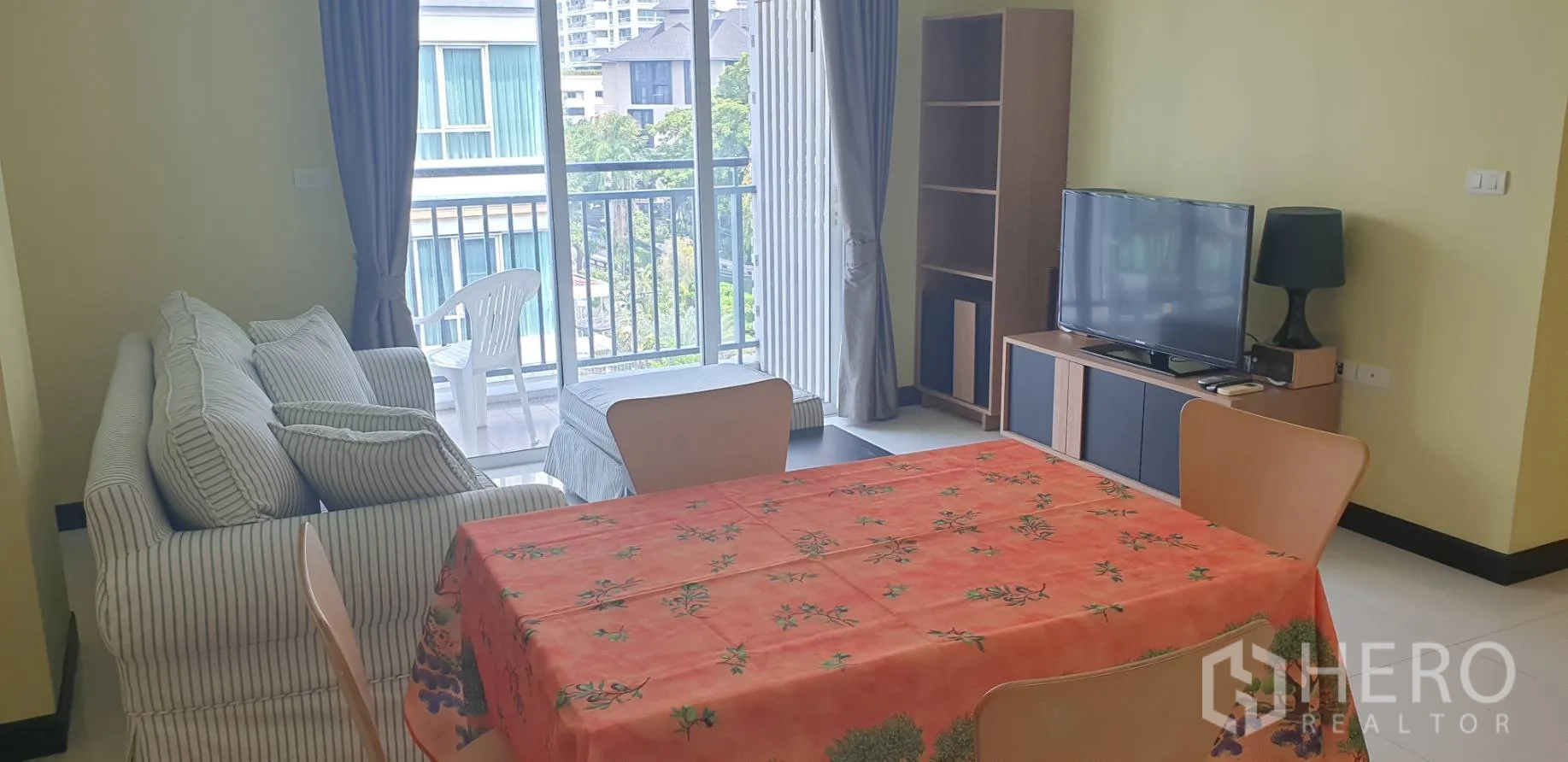 公寓 出租在Khlong Toei, Bangkok - 客餐厅一体，条纹沙发与橙色桌布，面向阳台景观。