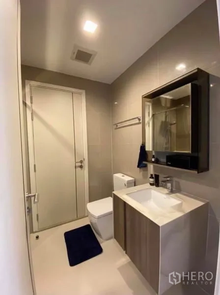 Condominium for rent or sale in Phaya Thai, Bangkok - Modern bathroom with vanity, mirror cabinet and toilet in neutral tones.