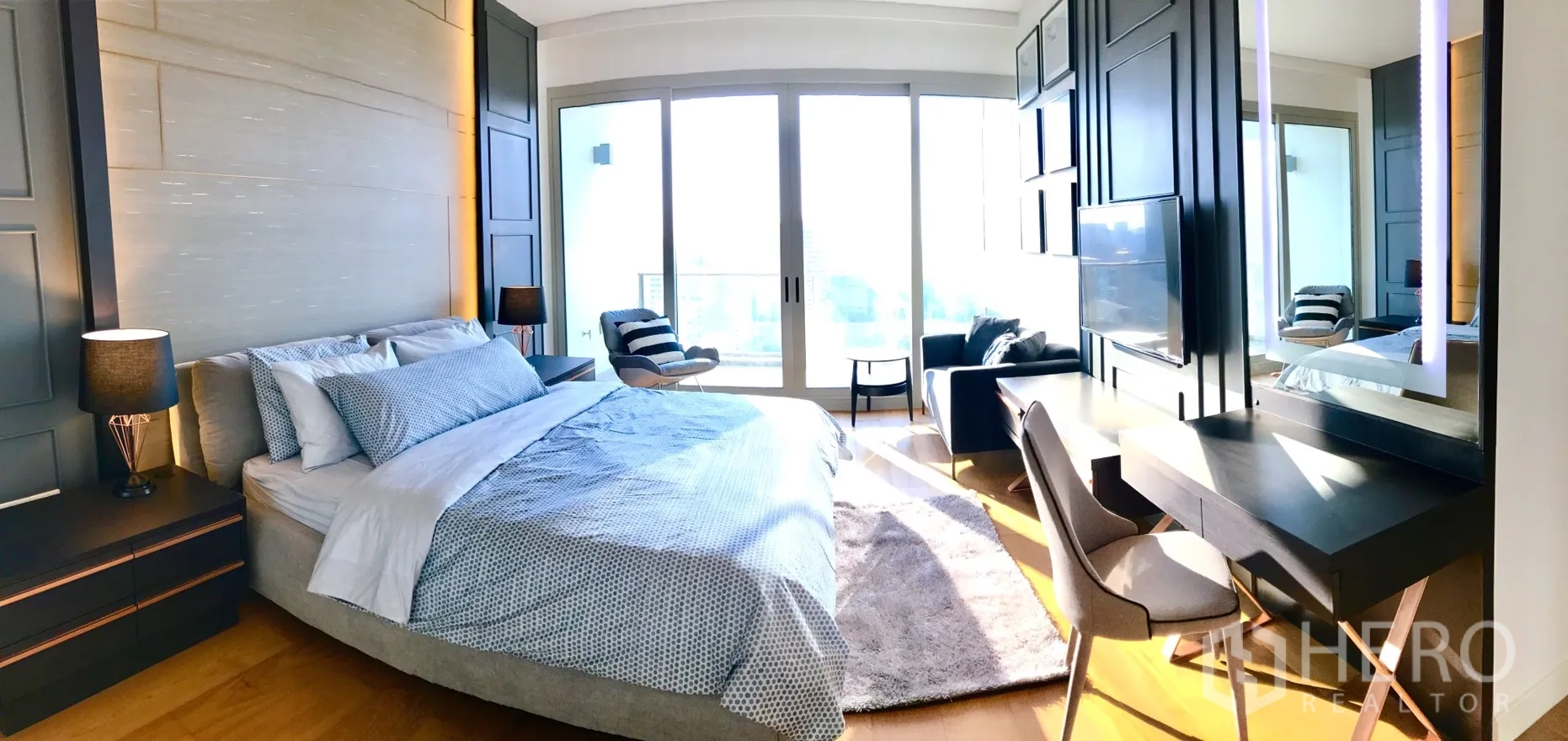 Condominium for rent in Pathum Wan, Bangkok - Bright bedroom with sliding doors to balcony, work desk and feature paneled wall.