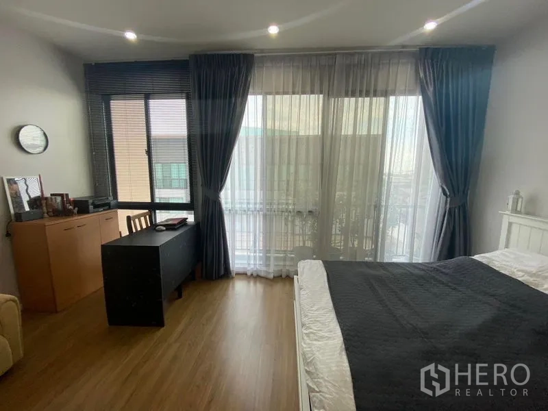 Townhouse for rent or sale in Saphan Sung, Bangkok - Master bedroom view showing study desk, cabinet and sliding doors to a balcony.