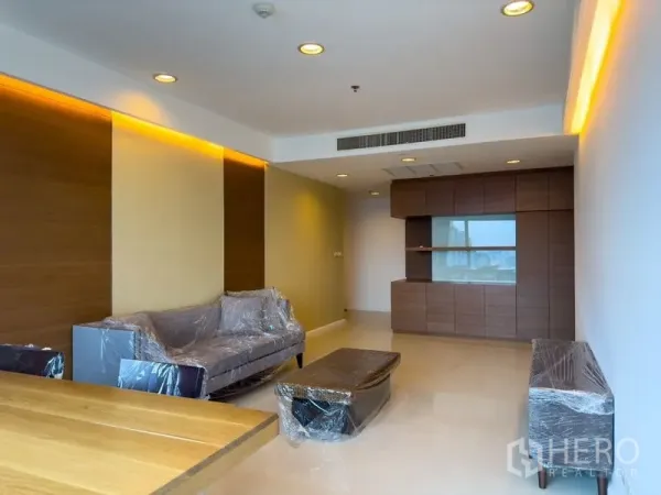 Condominium for rent or sale in Pathum Wan, Bangkok - Bright living room with recessed lighting, built‑in cabinet and sofa set wrapped for move‑in.