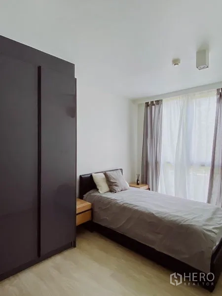 Condominium for rent in Pathum Wan, Bangkok - Second bedroom with single bed, large wardrobe and sheer curtains.