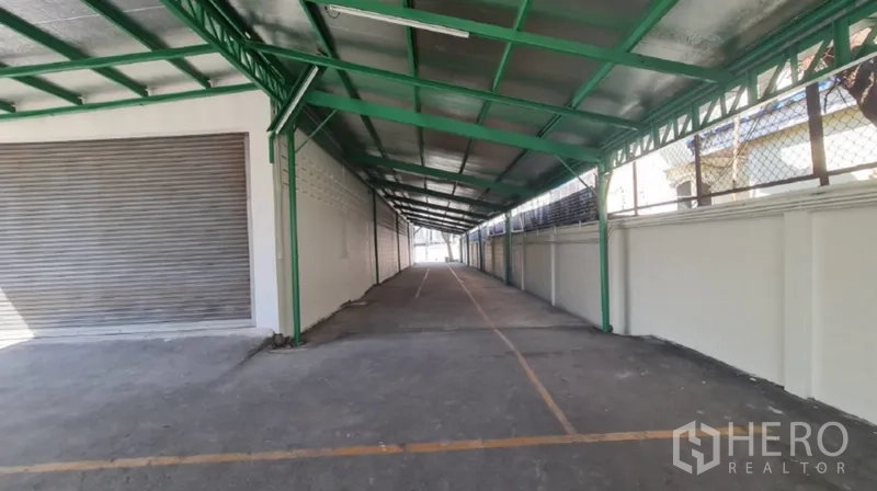 Warehouse for rent in Khlong Toei, Bangkok - Covered loading lane with green roof and marked truck bays.