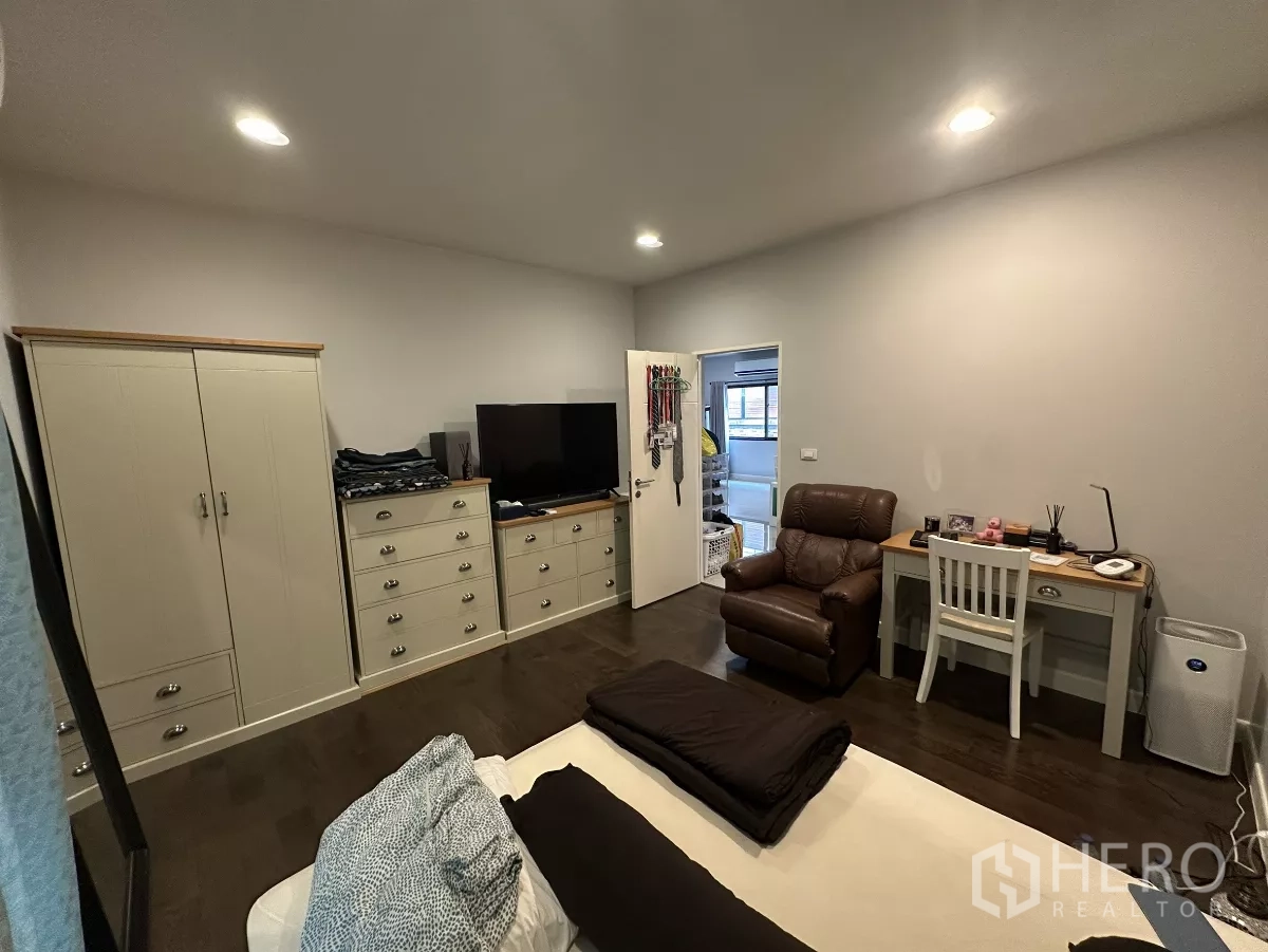 Detached House for rent or sale in Lam Luk Ka, Pathum Thani - Cozy bedroom with bed, wardrobes, TV cabinet, work desk and a recliner chair.
