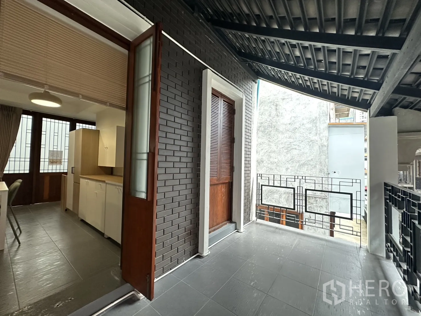 公寓 for rent in Pathum Wan, Bangkok - 半开放露台通向厨房区域，砖墙与木门相邻。