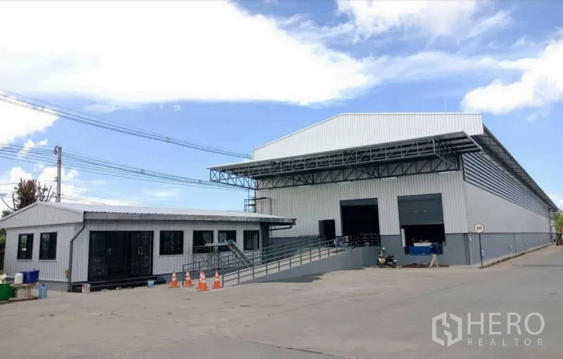 Warehouse for rent in Si Racha, Chon Buri - Panoramic exterior of warehouse and office with loading ramps and wide concrete yard