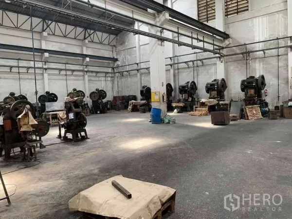 Factory for rent in Phra Samut Chedi, Samut Prakan - Open work area with heavy machinery lining the wall and ample maneuvering space.