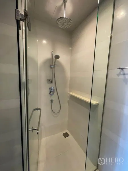 Condominium for rent in Khlong Toei, Bangkok - Close-up of glass shower with rainfall showerhead and handheld sprayer.