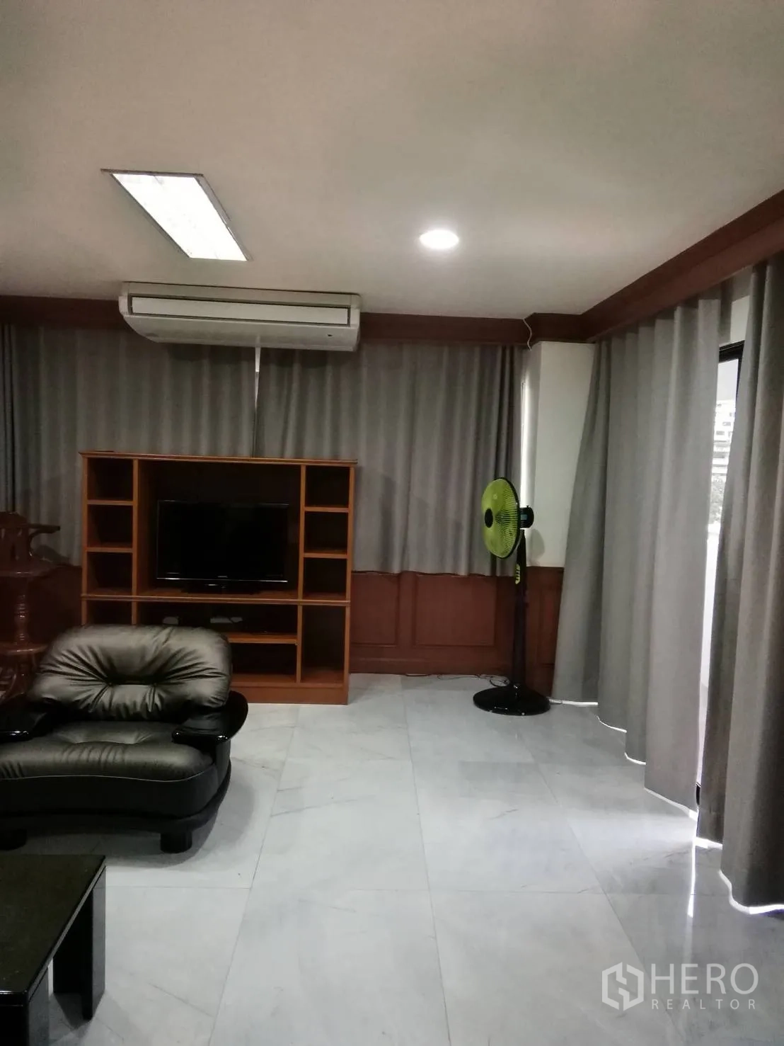 公寓 出租或出售在Watthana, Bangkok - 客厅一角设电视柜、分体空调与灰色遮光窗帘。