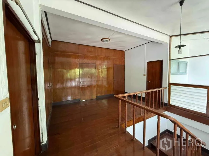 Detached House for rent in Watthana, Bangkok - Upstairs landing with wooden staircase and wall paneling.