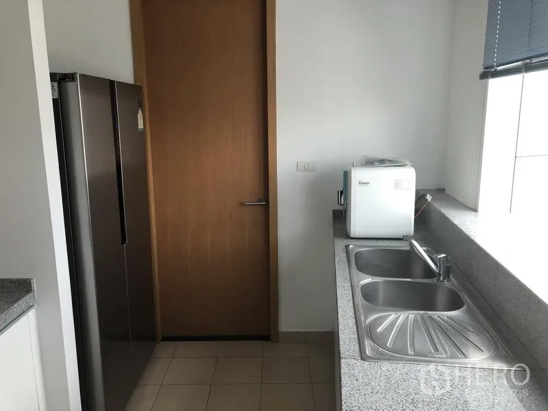 Condominium for rent in Khlong Toei, Bangkok - Kitchen utility zone with double stainless-steel sink, window blinds and large refrigerator.