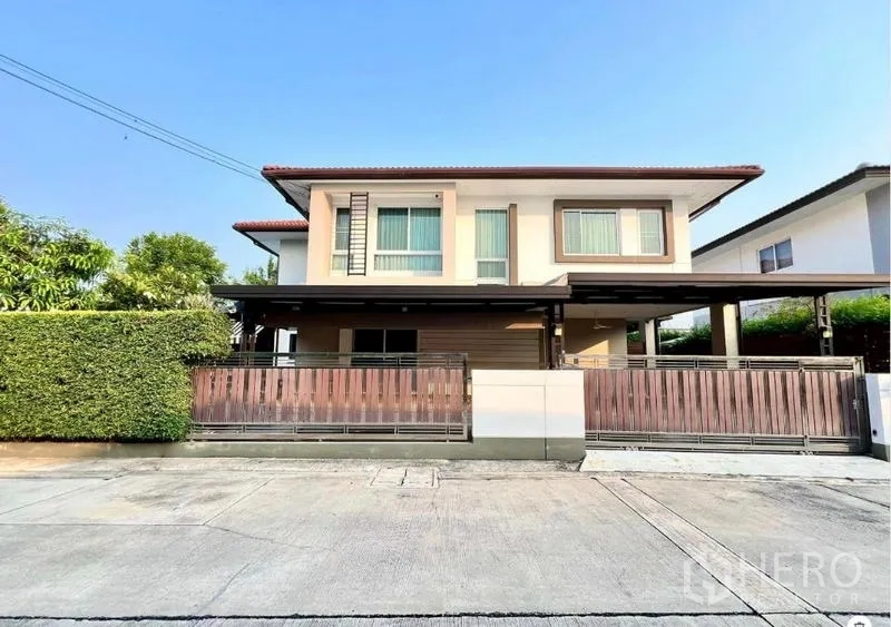 Detached House for sale in Bang Kruai, Nonthaburi - Front exterior view of the detached home with sliding wooden gate and covered parking.