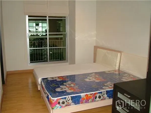 Condominium for rent in Khlong Toei, Bangkok - Bright bedroom with a double bed, large window with blinds, and garden-side outlook.