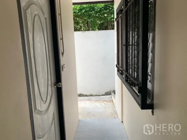 Detached House for rent in Khlong Toei, Bangkok - Narrow side corridor with security-grilled window and a door opening to a small yard.