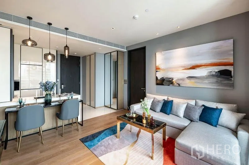 Condominium for rent in Khlong Toei, Bangkok - Open-plan living and dining area with wood floors, mirrors and pendant lights