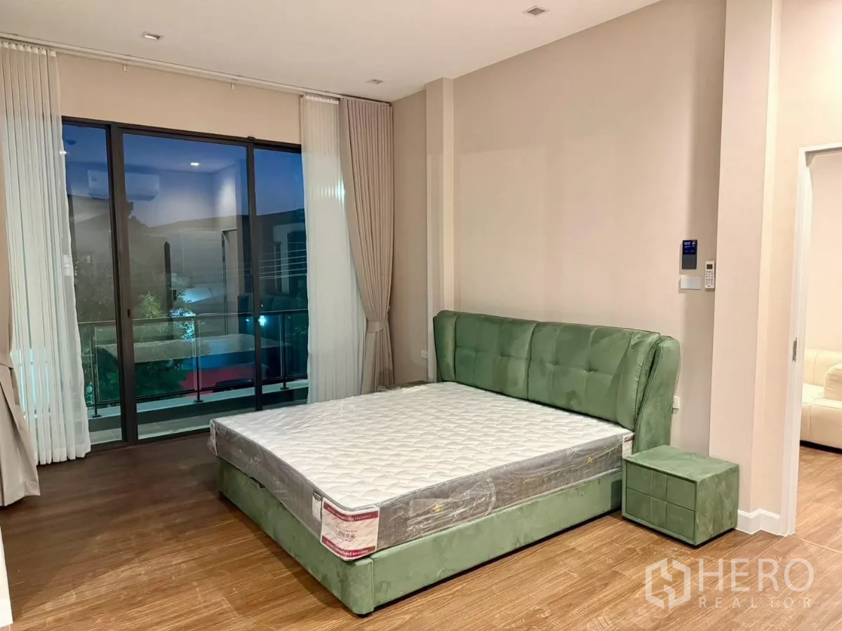 独立式住宅 出租在Bang Phli, Samut Prakan - 主卧配绿色软包床，连接观景阳台。