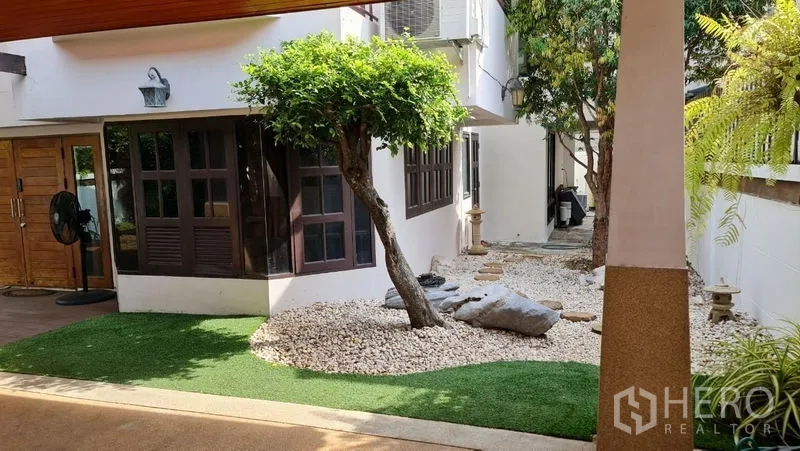 Detached House for rent in Saphan Sung, Bangkok - Zen rock garden with artificial grass and bay windows along the side of the house.