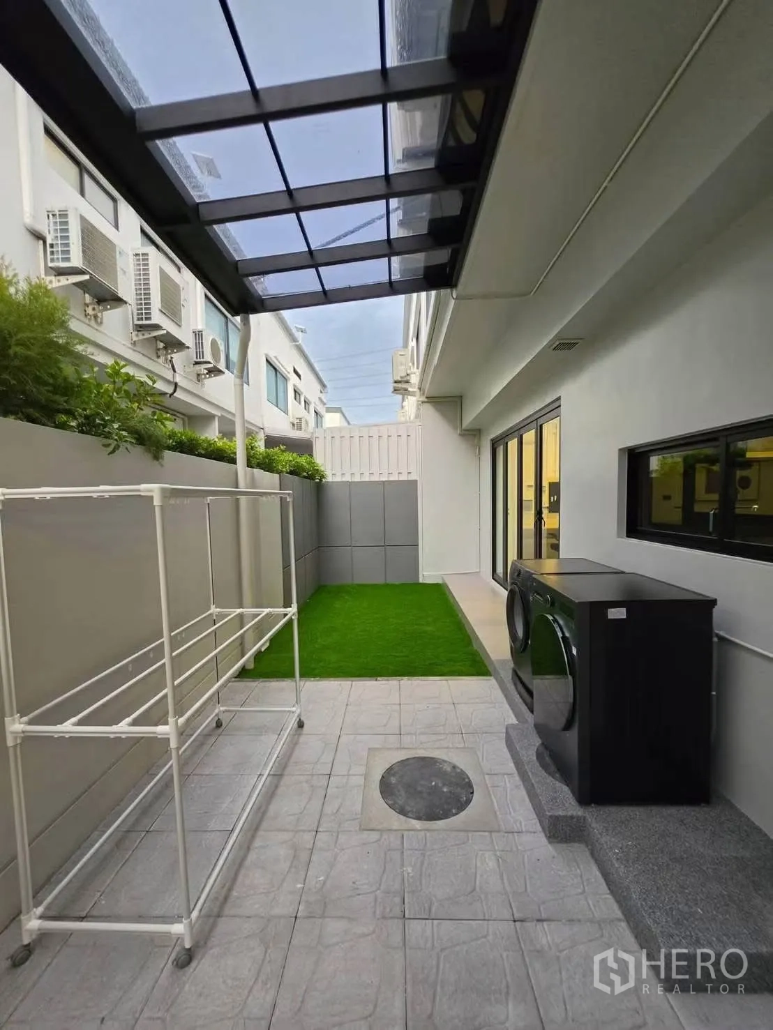 Townhouse for rent in Bang Phli, Samut Prakan - Covered utility yard with washer, drying rack, and a strip of artificial lawn.