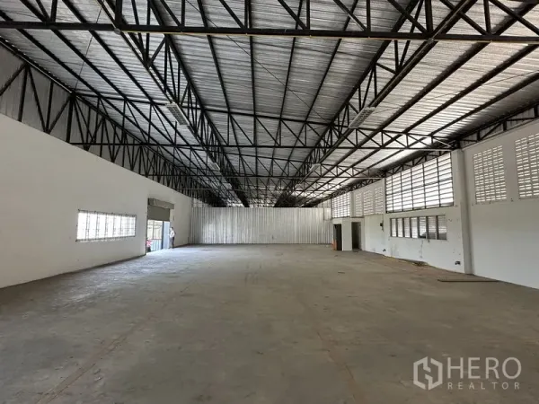 Factory for rent in Lam Luk Ka, Pathum Thani - Wide warehouse hall showing roller door entry and metal-clad rear wall.