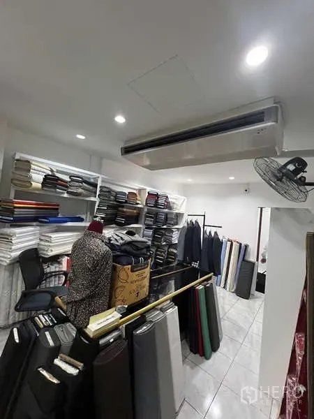 Retail Space for rent in Khlong Toei, Bangkok - Stock room with fabric rolls, white shelving and a wall-mounted air conditioner.