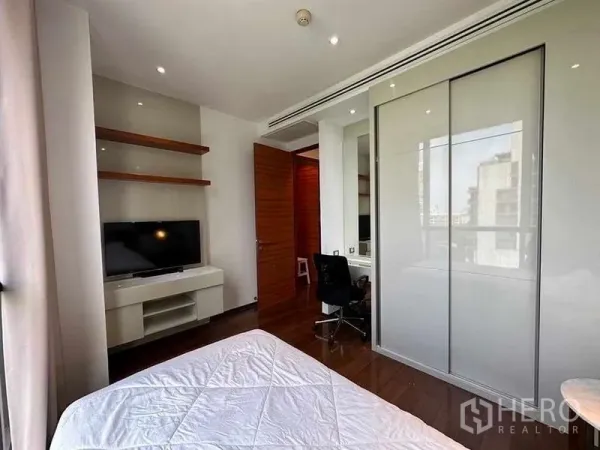 公寓 出租在Khlong Toei, Bangkok - 卧室配电视与置物架、滑动衣柜及书桌工作区。