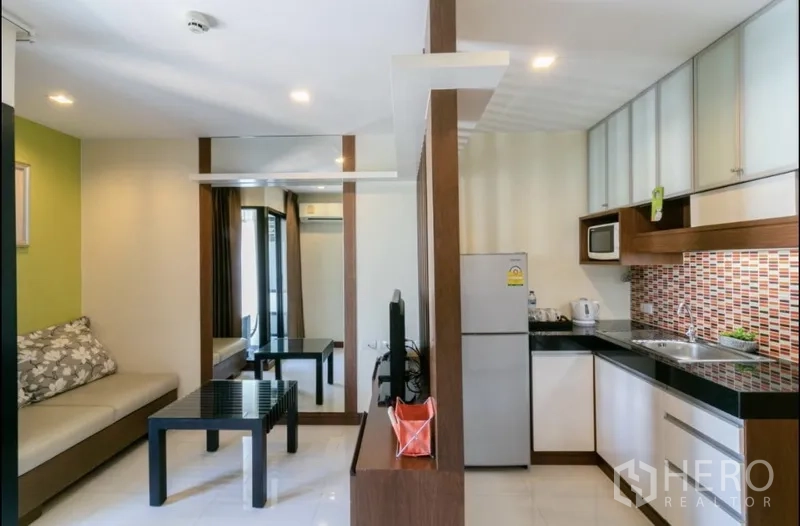 房间 出租在Bang Rak, Bangkok - 开放式起居与现代小厨房，配冰箱、微波炉和彩色马赛克墙面。