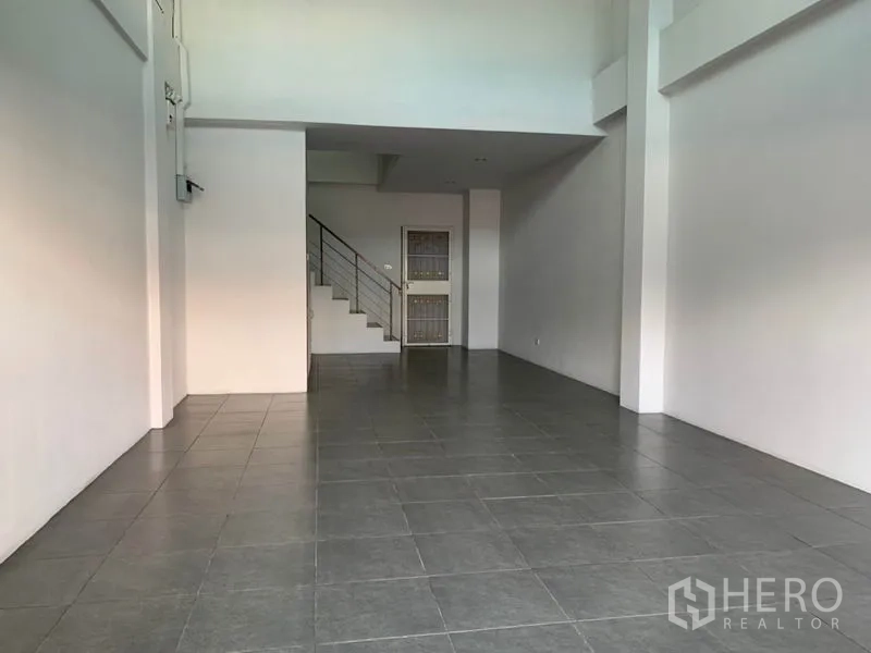 店屋 出售在Lat Phrao, Bangkok - 开阔开放式店面大厅，挑高天花、瓷砖地面与上楼梯。