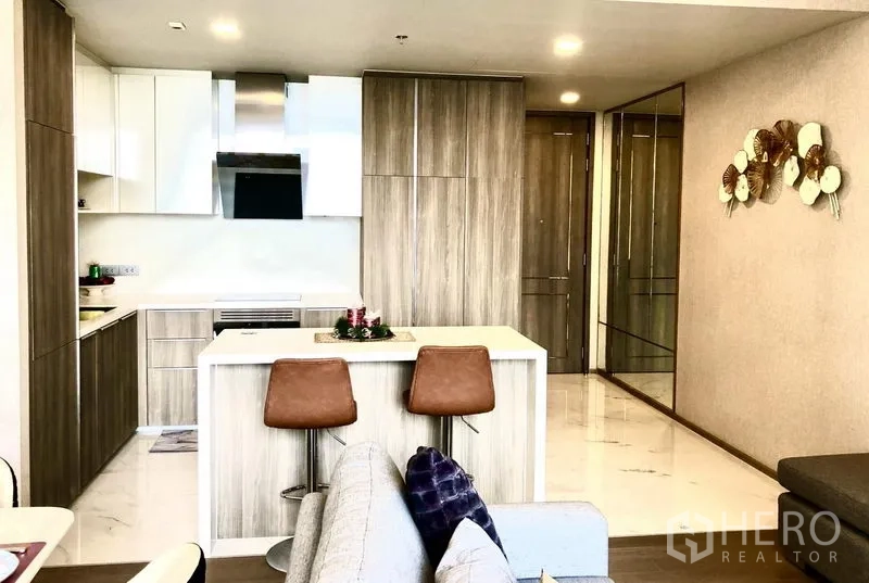 公寓 出租在Watthana, Bangkok - 采光充足的现代厨房，木纹柜体与白色台面，设中岛与吧椅。