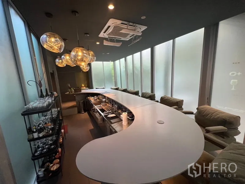 Retail Space for rent in Khlong Toei, Bangkok - Long curved service bar with plush stools and modern ceiling lights facing frosted glass panels.