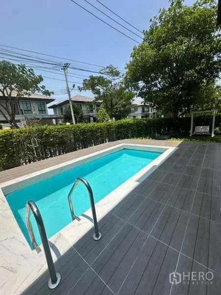 独立式住宅 出售在Prawet, Bangkok - 从平台望泳池，绿篱与社区树木、邻屋可见。
