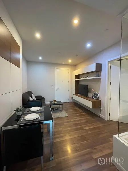 公寓 出租或出售在Phra Khanong, Bangkok - 温馨木地板客厅，壁挂电视柜、双人餐桌与筒灯照明