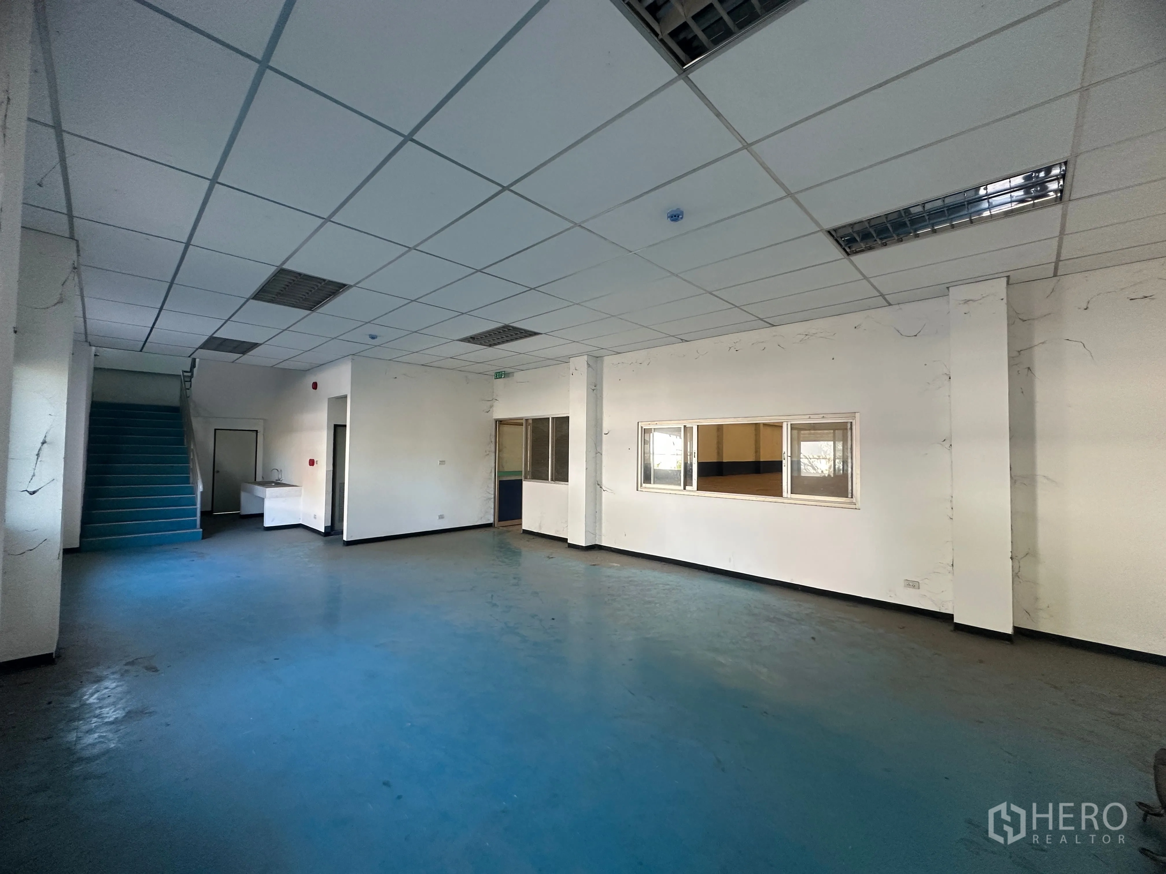 โรงงาน for rent in Bang Pa-in, Phra Nakhon Si Ayutthaya - โถงสำนักงานชั้นล่างพื้นสีน้ำเงินพร้อมบันไดและหน้าต่างมองเข้าโรงงาน