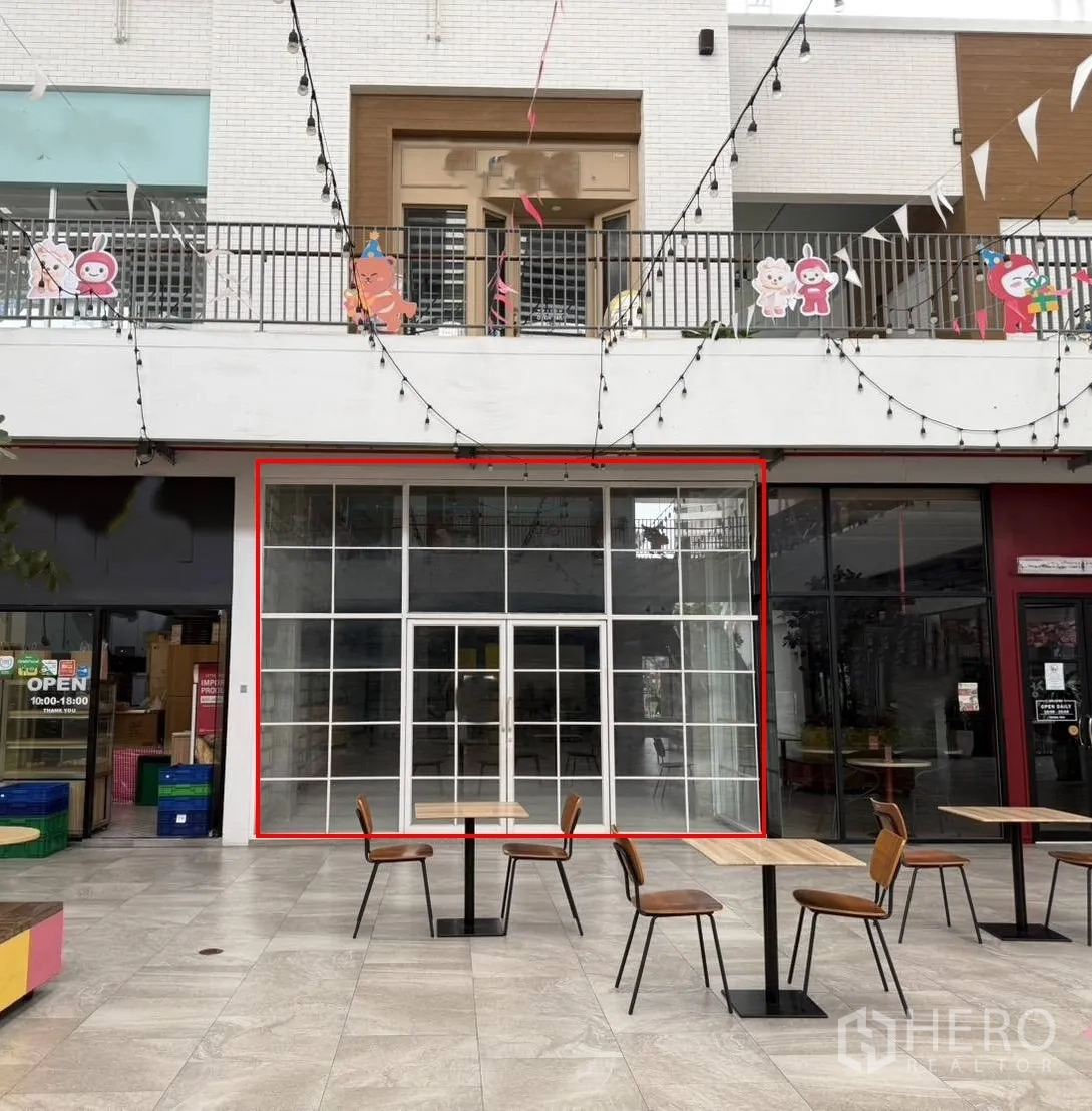 零售空间 for rent in Khlong Toei, Bangkok - 店铺外立面为大面积玻璃，朝向设有桌椅与灯串的庭院。