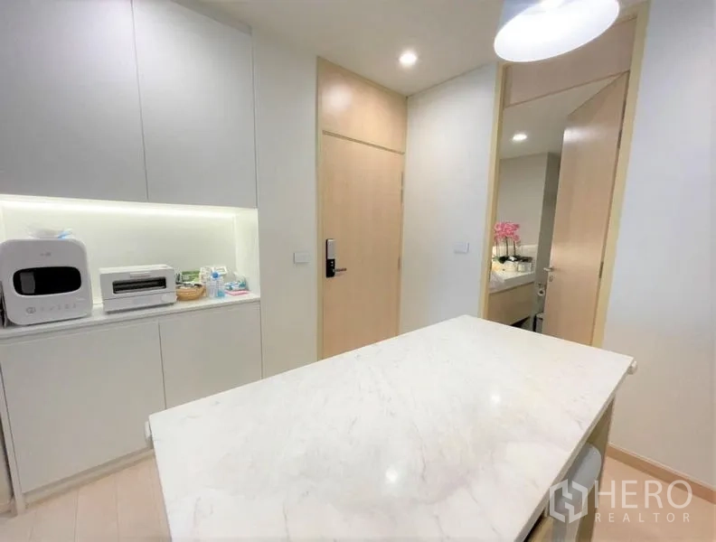Condominium for rent or sale - Pantry area with marble-topped island, backlit built-in cabinetry and doorway to the bathroom.