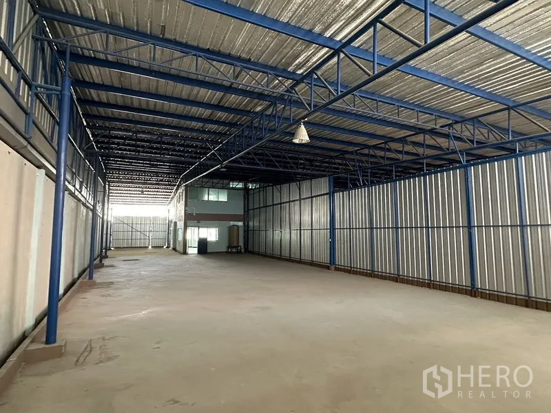 Warehouse for rent in Bueng Kum, Bangkok - Large open warehouse hall with blue steel trusses, corrugated walls and high ceiling lights.