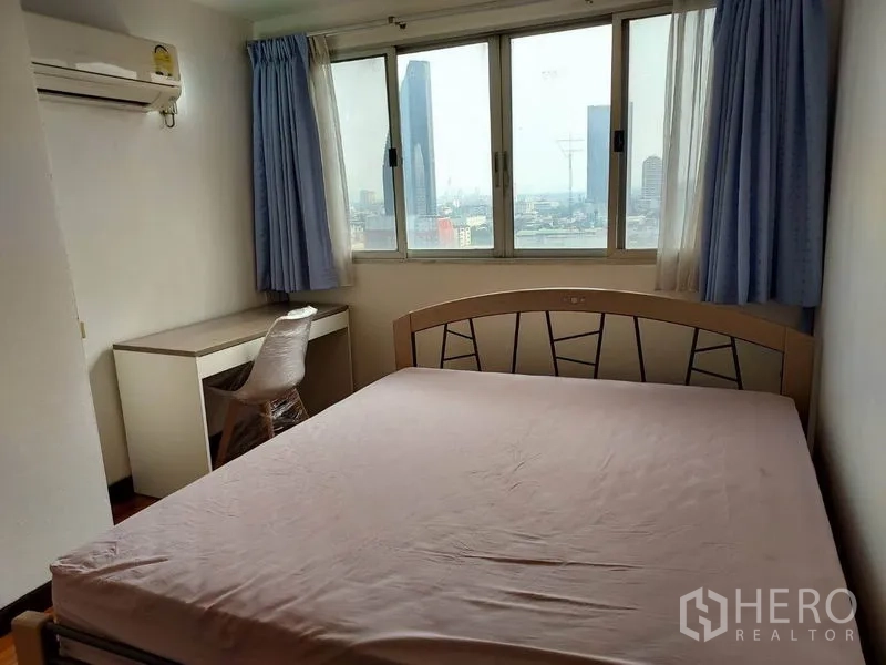 Condominium for rent or sale in Khlong Toei, Bangkok - Bright bedroom with large window, desk and wide city view.