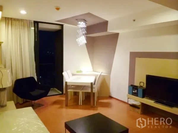 公寓 出租在Watthana, Bangkok - 客餐厅一体空间，通向阳台，水晶吊灯与电视墙。