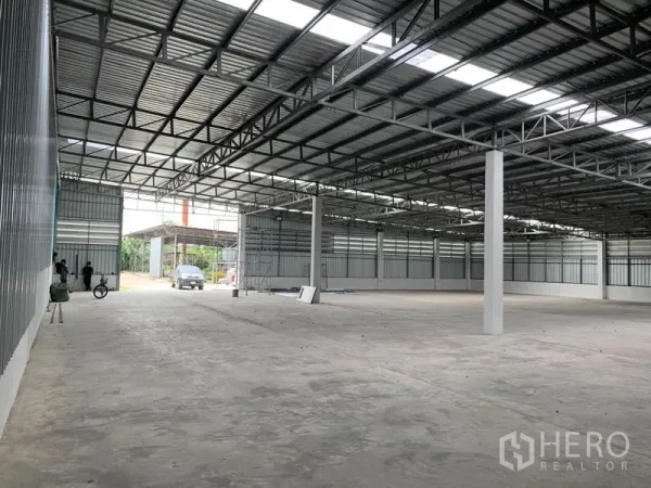 Warehouse for rent in Mueang Pathum Thani, Pathum Thani - Spacious clear-span warehouse interior with high steel truss roof, skylights and polished concrete floor.