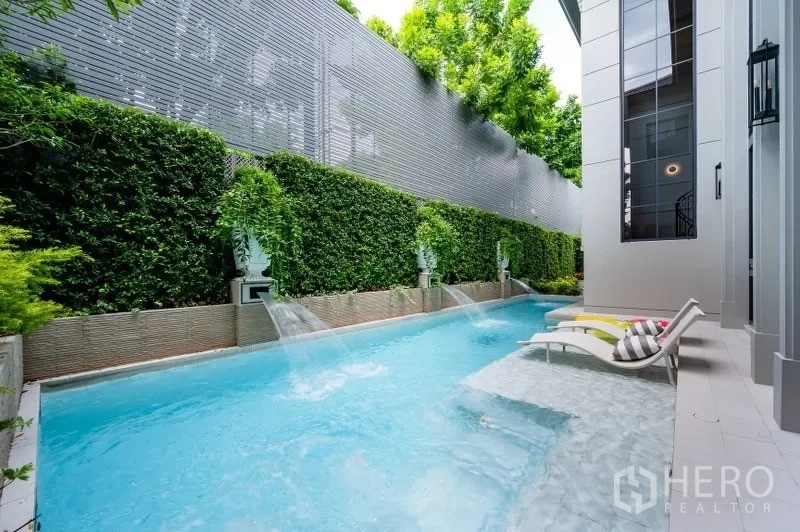 Detached House for sale in Bang Kapi, Bangkok - Private lap pool with water features, tall privacy hedge and sun loungers on a shallow ledge.