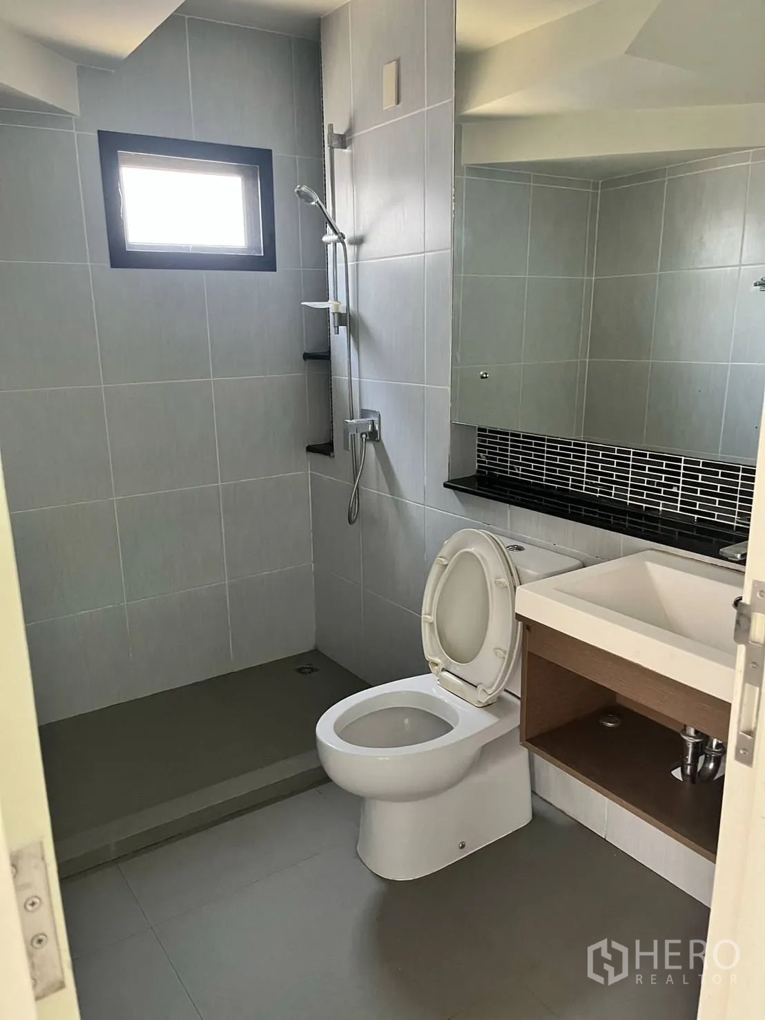 Detached House for rent or sale in Lam Luk Ka, Pathum Thani - Bathroom with grey tiles, shower area and large mirror.